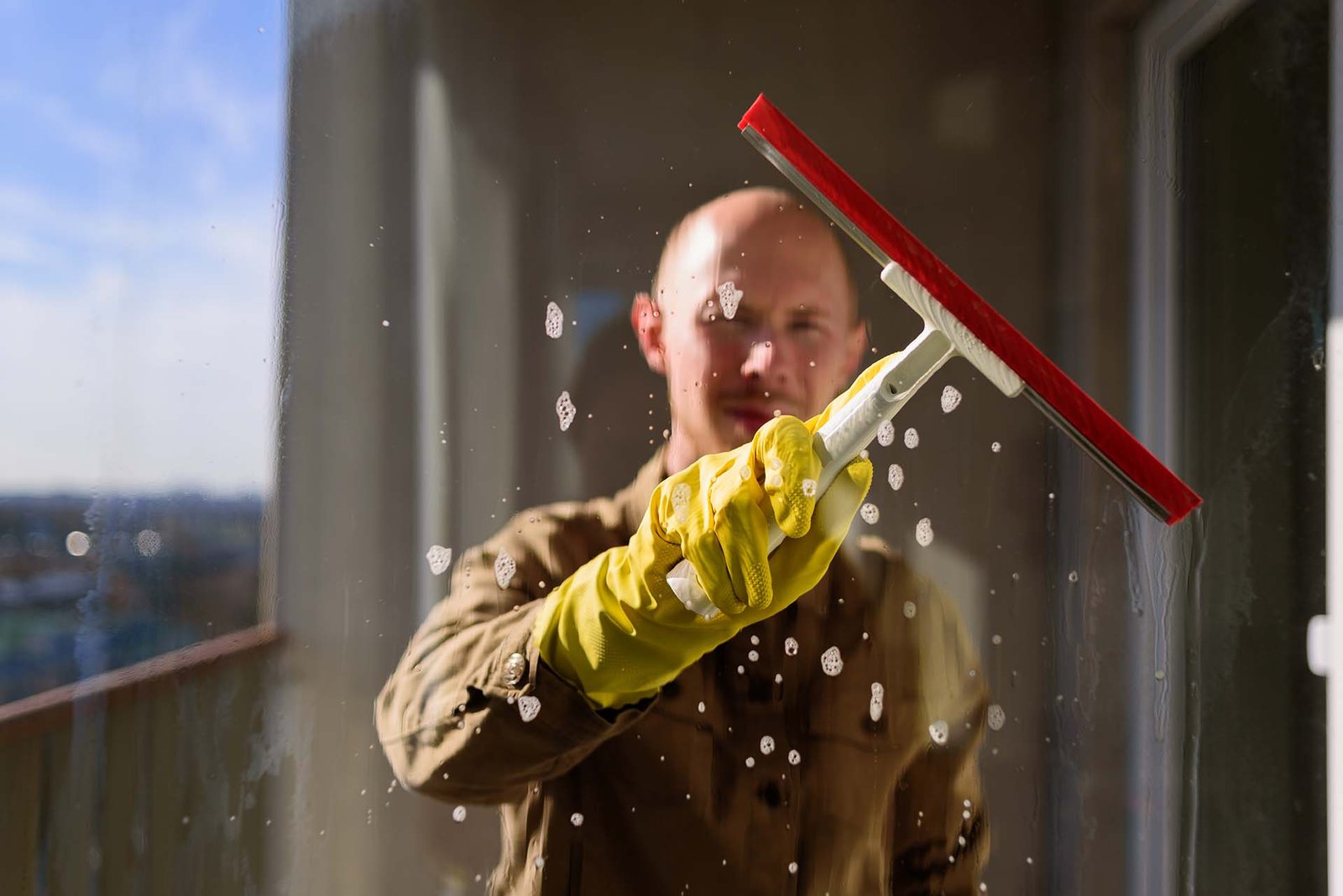 Man washing window in yellow rubber gloves